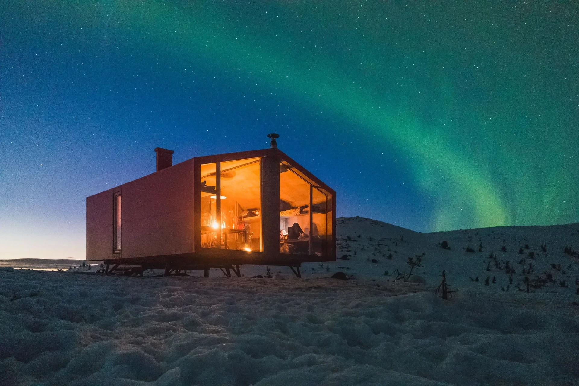 Lit cabin under northern lights