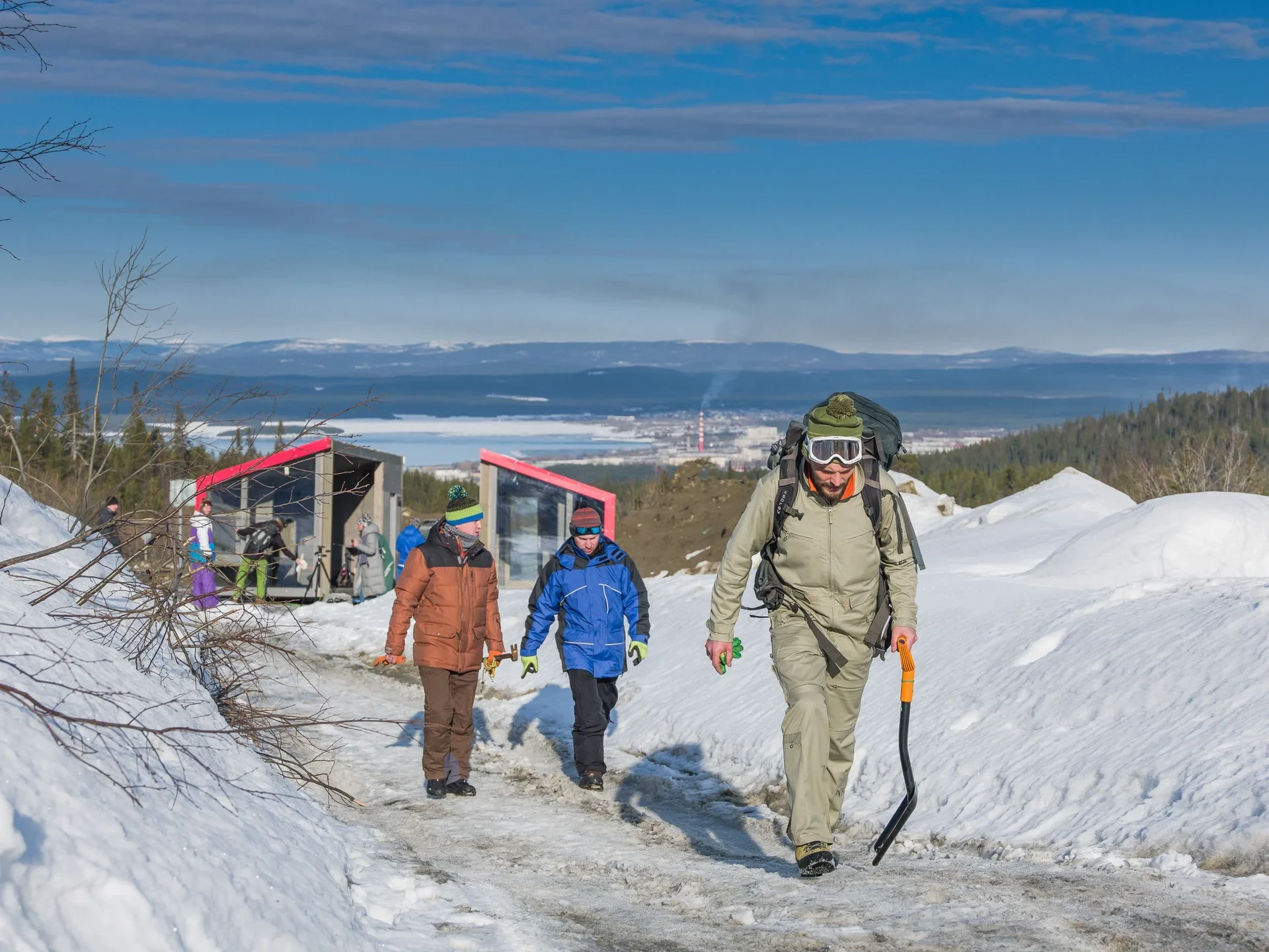 Hikers climbing snowy path toward cabin