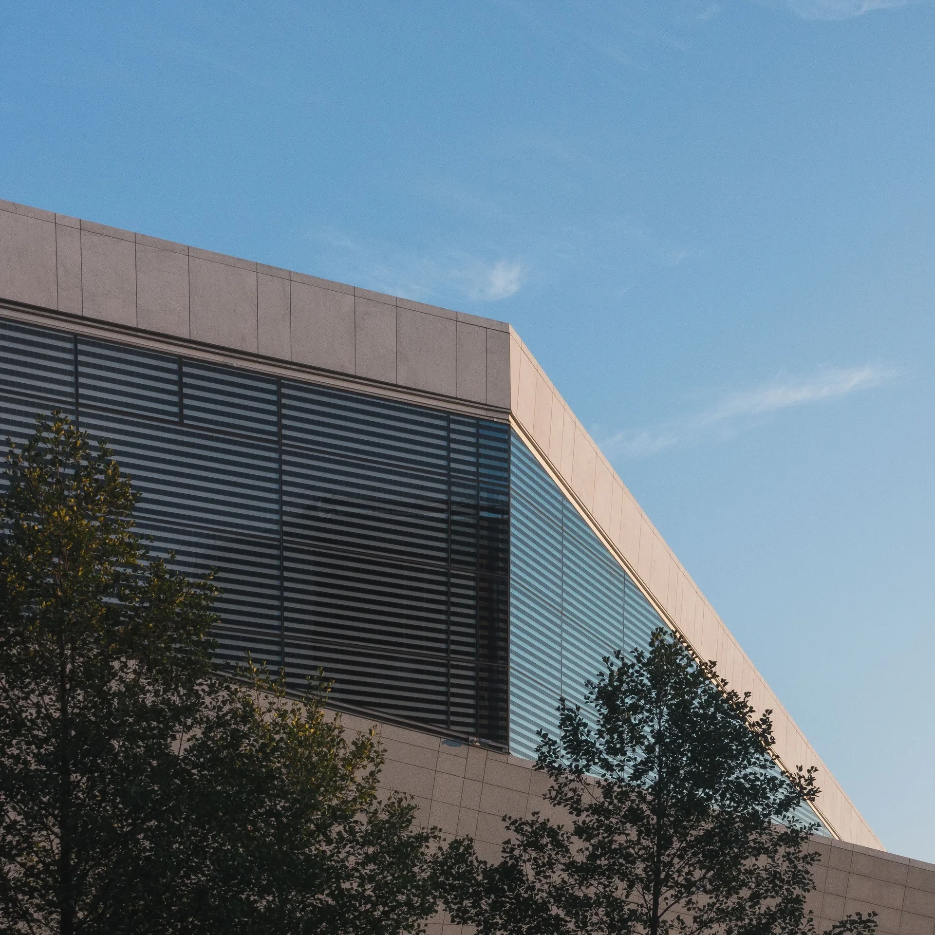 Building corner with louvred windows against blue sky