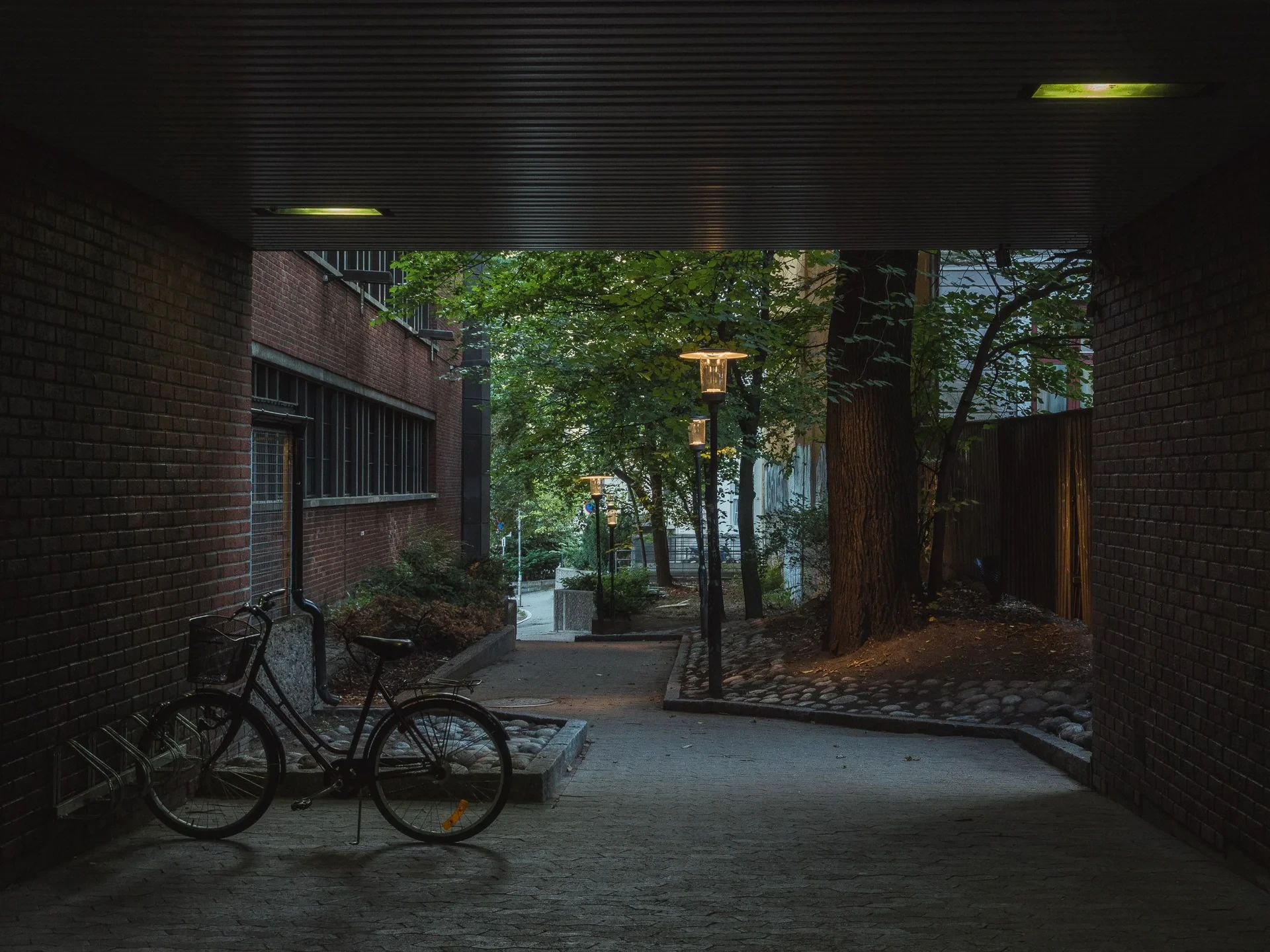 Bicycle in a passage looking onto a lit courtyard