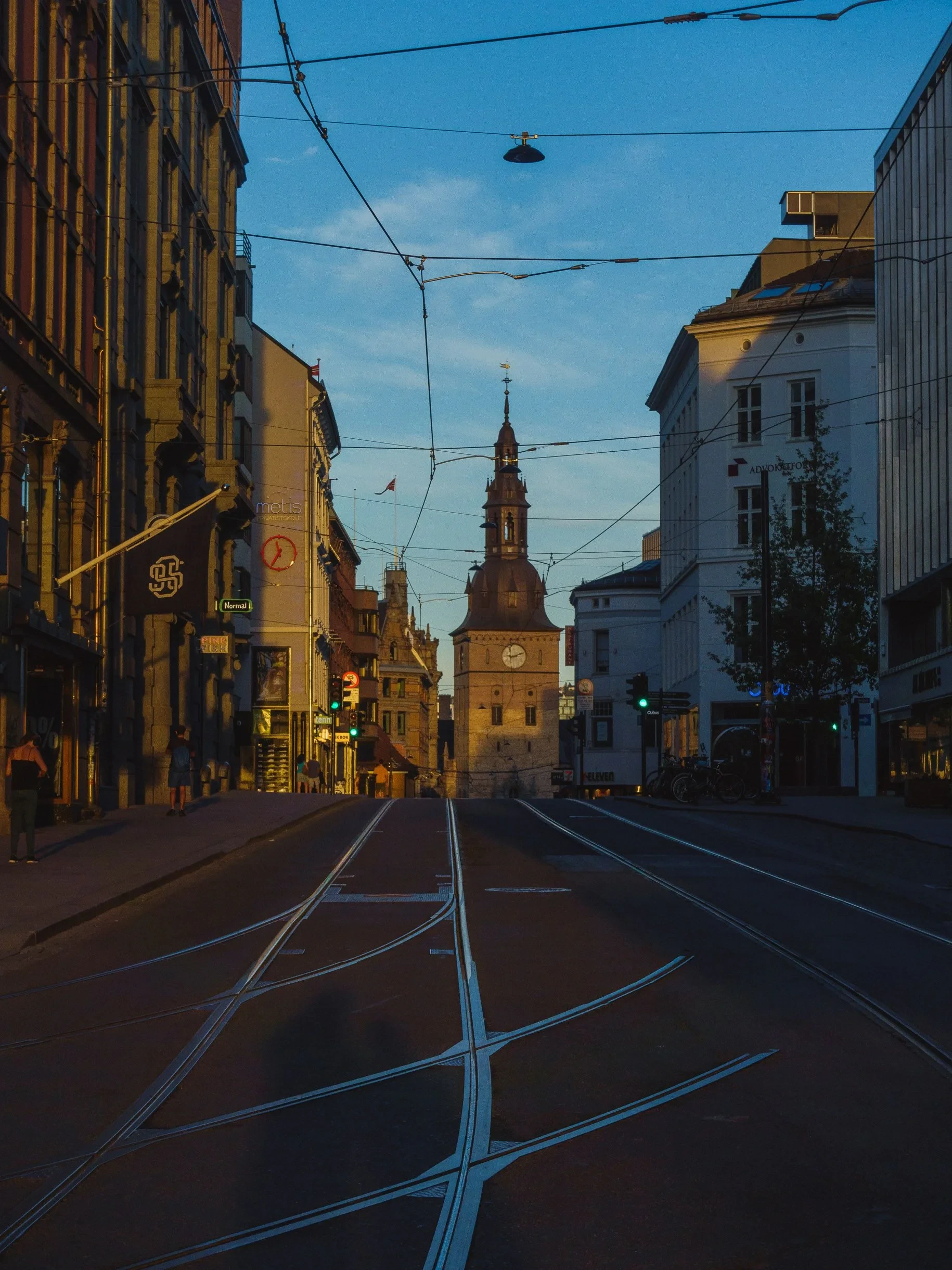 Tram tracks toward a clock tower at dusk