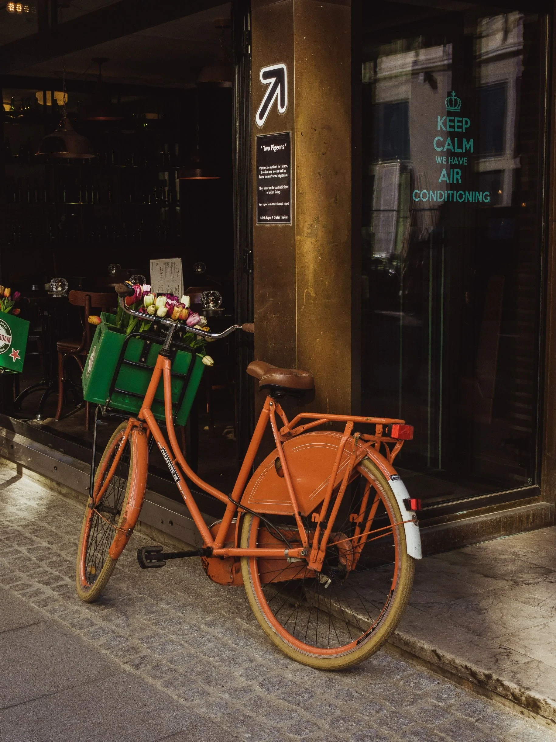 Orange bicycle with flowers outside a cafe