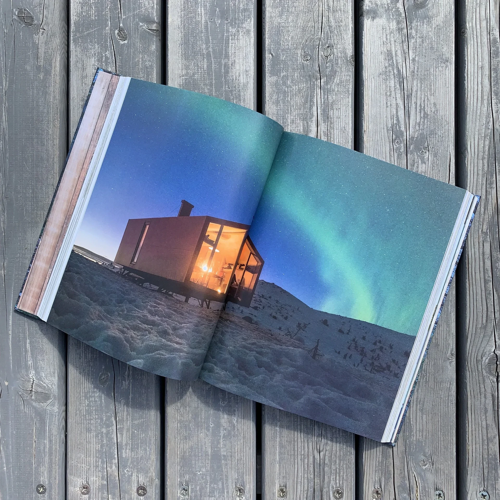 Book spread of cabin under northern lights