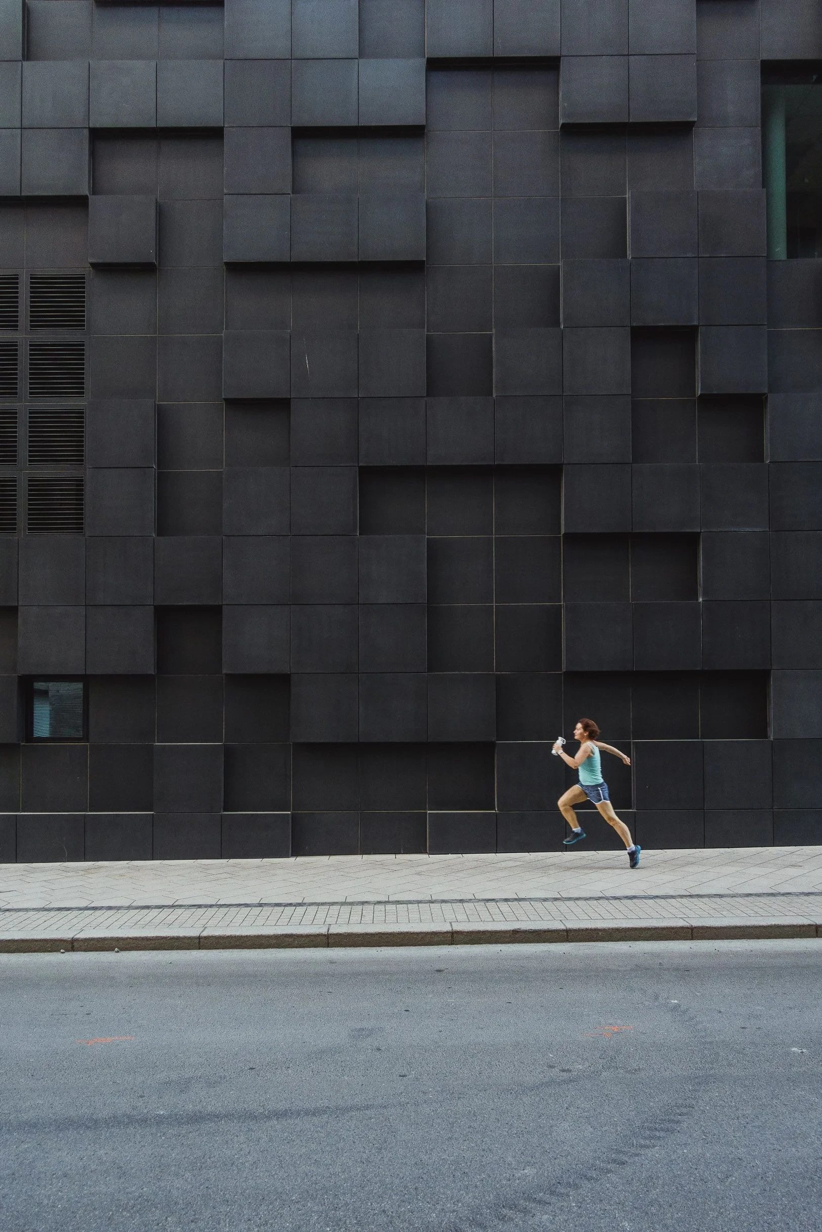 Runner sprinting past a dark tiled wall